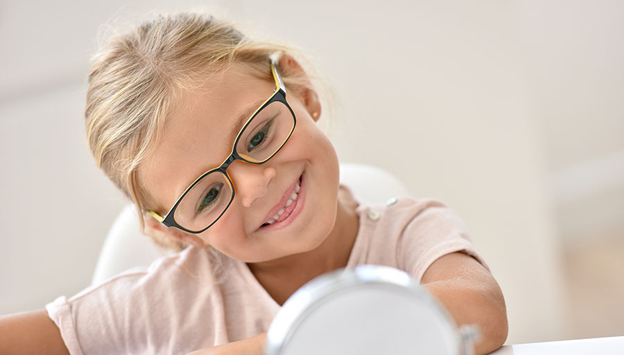 Child eyewear pediatric girl trying on glasses and smiling